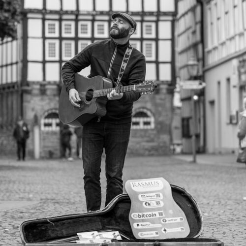 Rasmus Schumacher spielt Gitarre bei der Straßenmusik vor einem Fachwerkhaus – Schwarz-Weiß