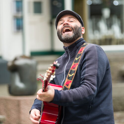 Rasmus Schumacher singt und spielt rote Akustikgitarre auf der Straße